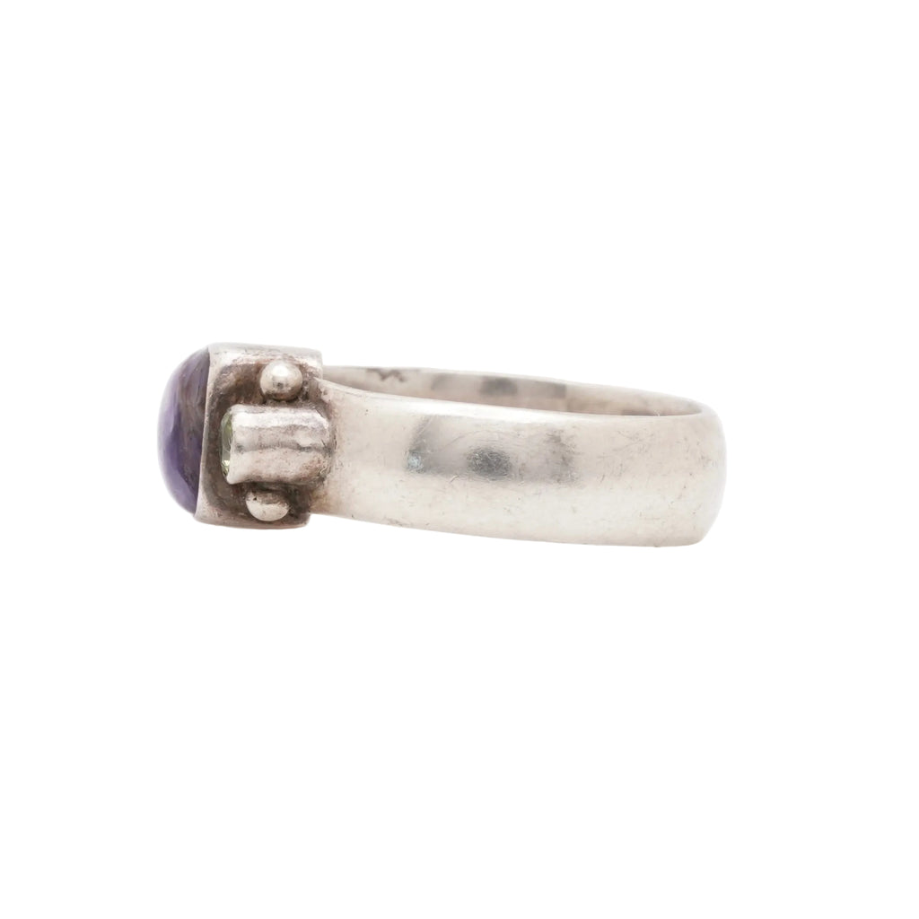 Silver ring with a purple stone on a white background