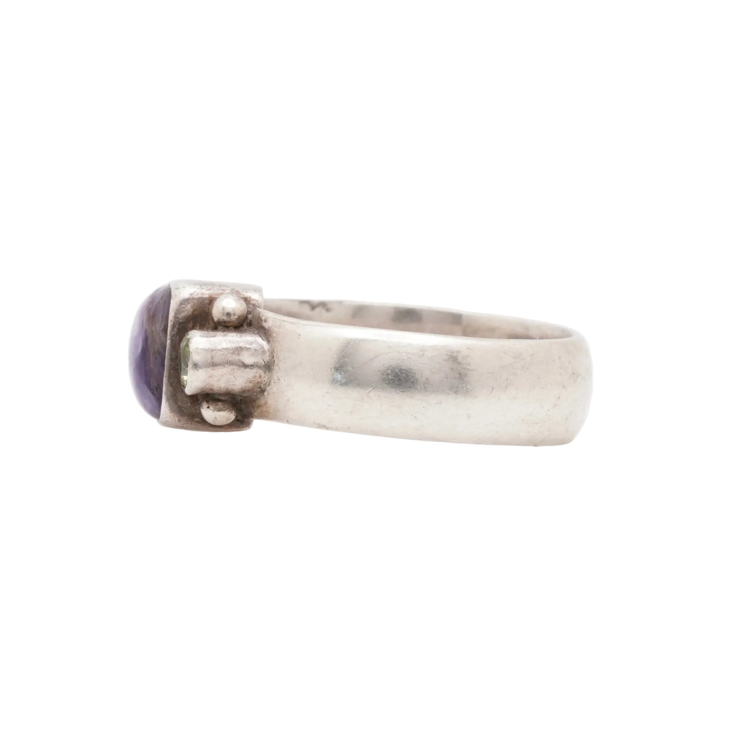 Silver ring with a purple stone on a white background