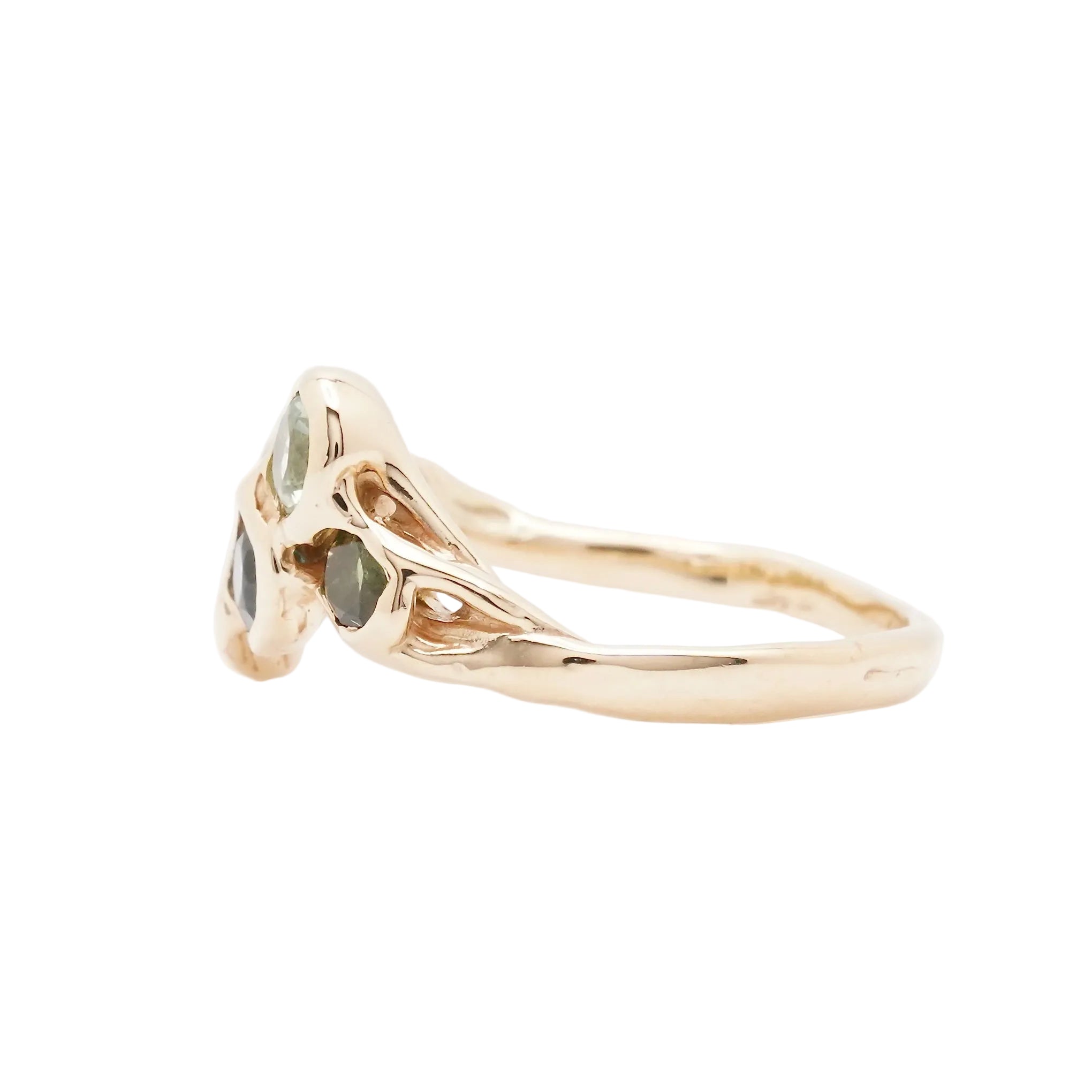 A gold ring with three small green gemstones in a triangular setting, shown on a plain white background.