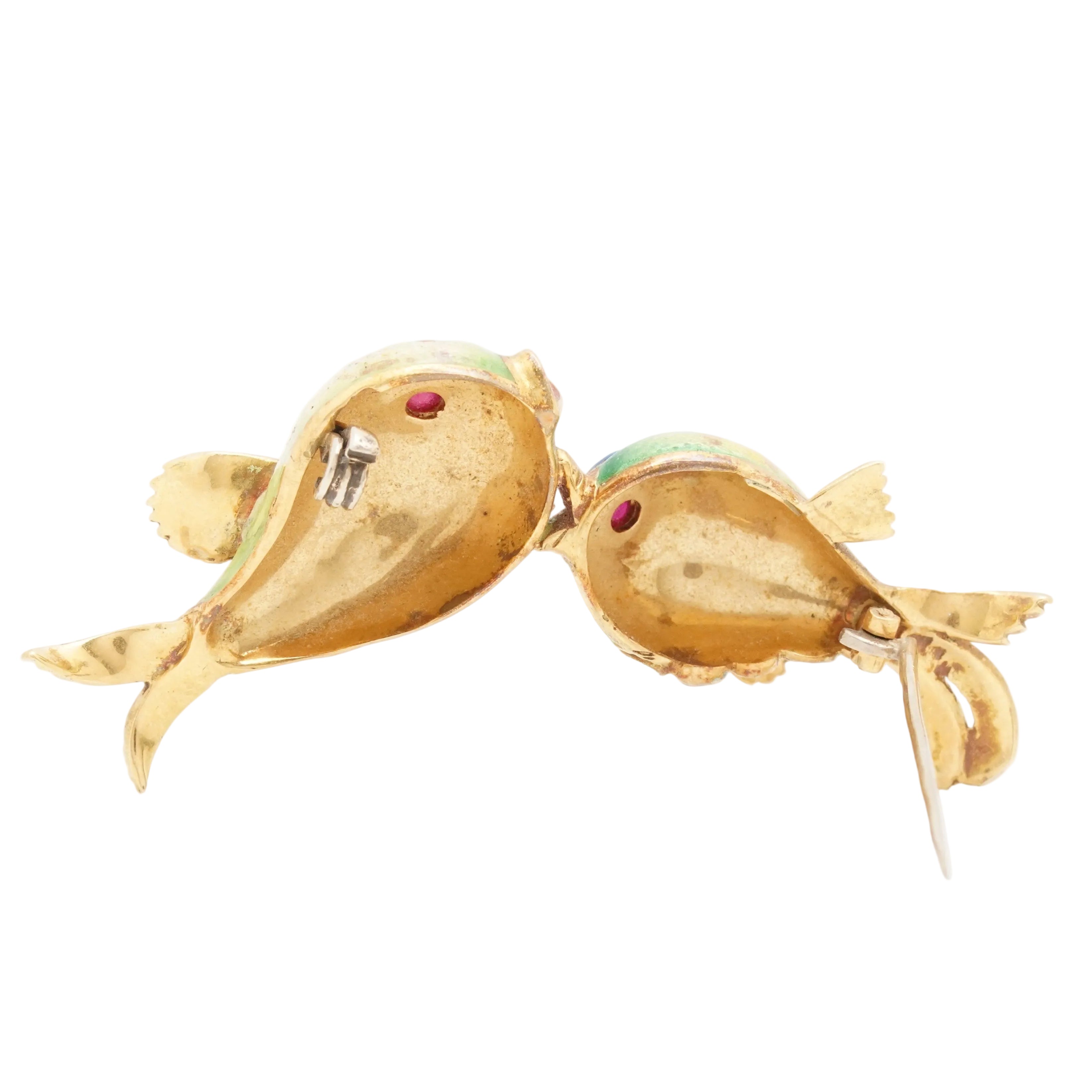 Gold fish-shaped brooch with gemstones on a white background