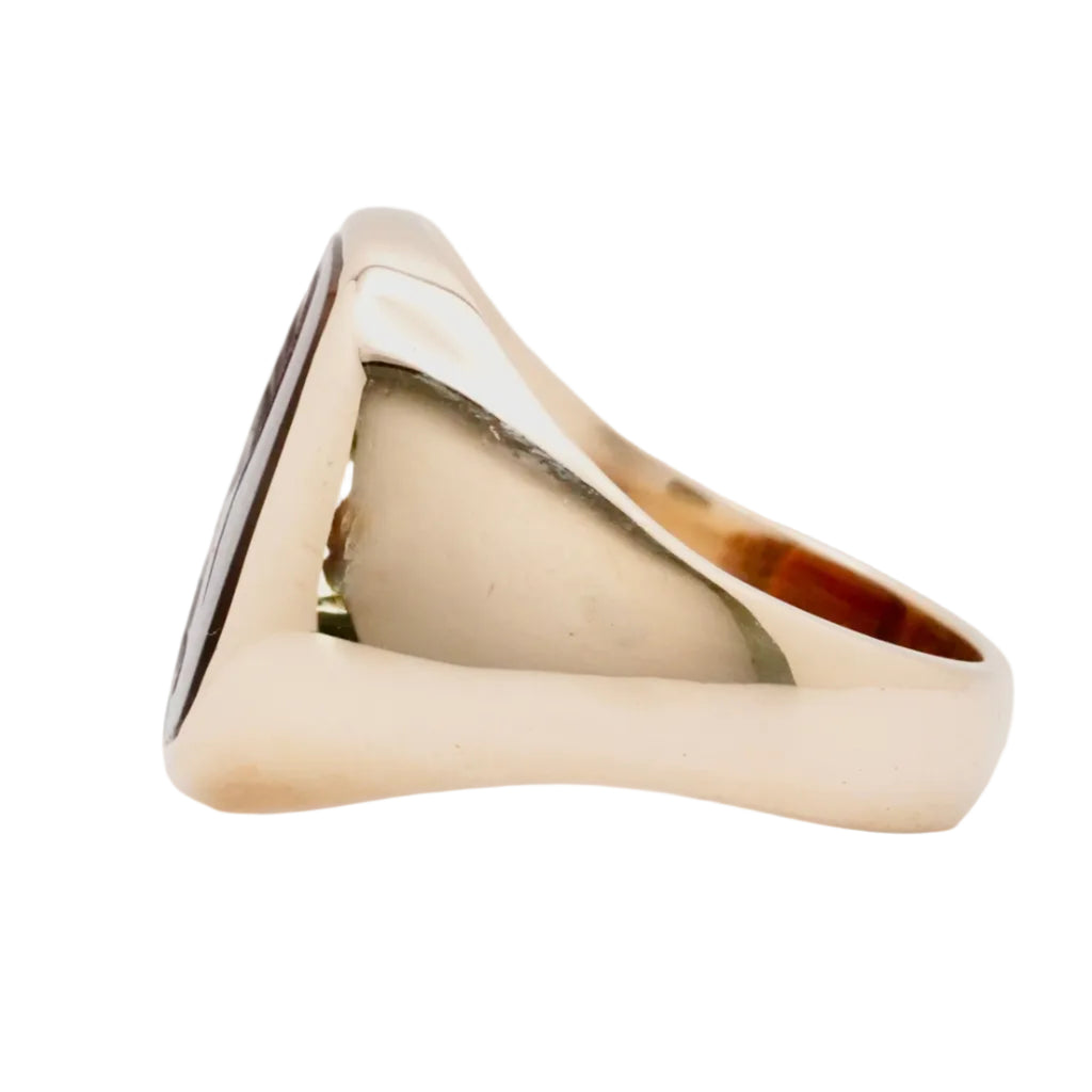 Gold signet ring with an intaglio gemstone on a white background