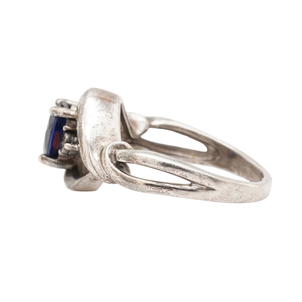 Side view of a vintage sterling silver ring showing the oval synthetic sapphire and diamond side stones