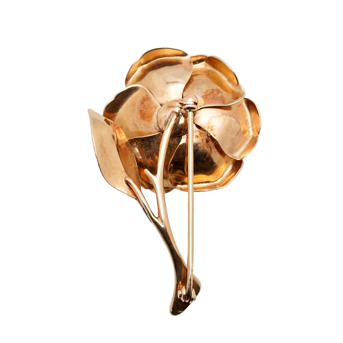 A polished gold-tone metal flower brooch with layered petals and a branch-like stem, photographed on a clean white background.
