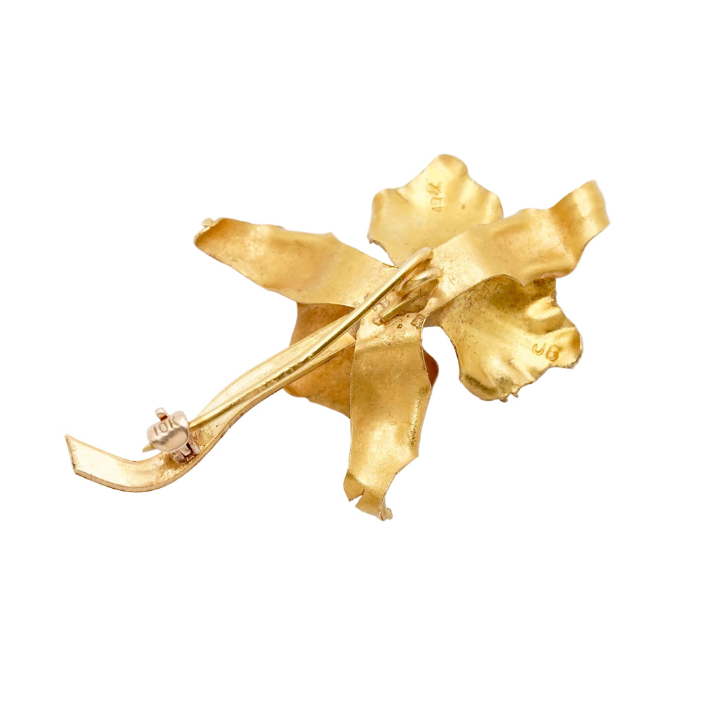 A vintage gold iris flower-shaped brooch with a textured, organic leaf-like design and a visible pin clasp, shown on a plain white background.